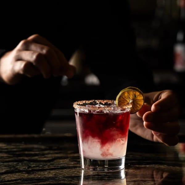 Bartender garnishing a red and white cocktail with a dried orange slice at Primavera Ristorante.