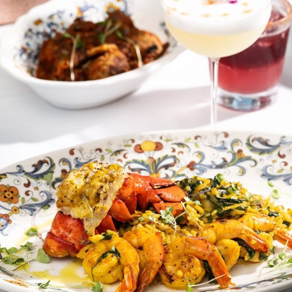 Primavera Ristorante's lobster and shrimp dish with risotto, garnished with microgreens, and cocktails.