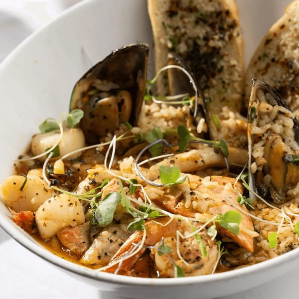 Close-up of Primavera Ristorante's seafood risotto with mussels, scallops, and garlic bread.